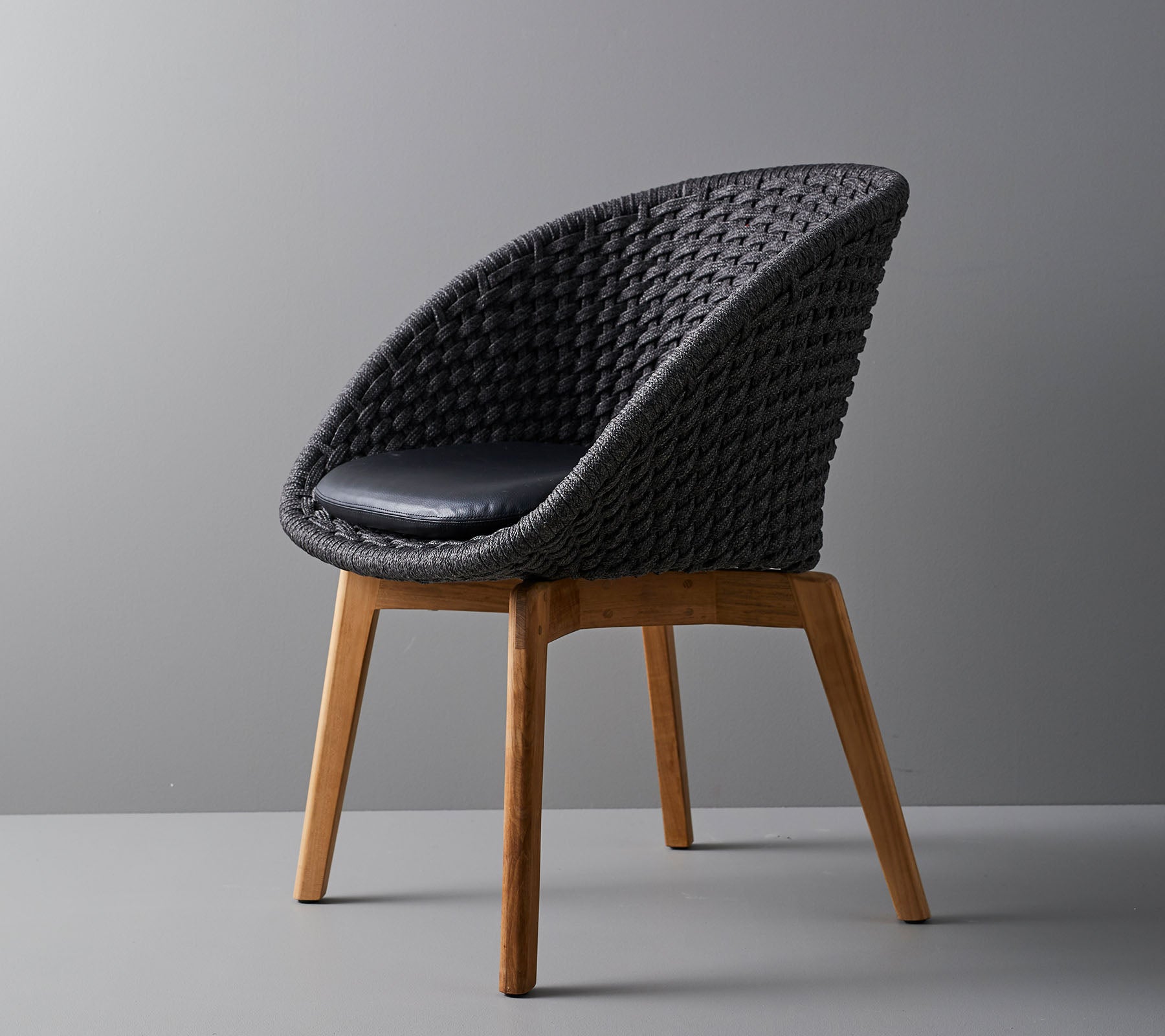 Stylish woven chair with a comfortable cushion, featuring smooth, tapered wooden legs and a modern design suitable for various settings.