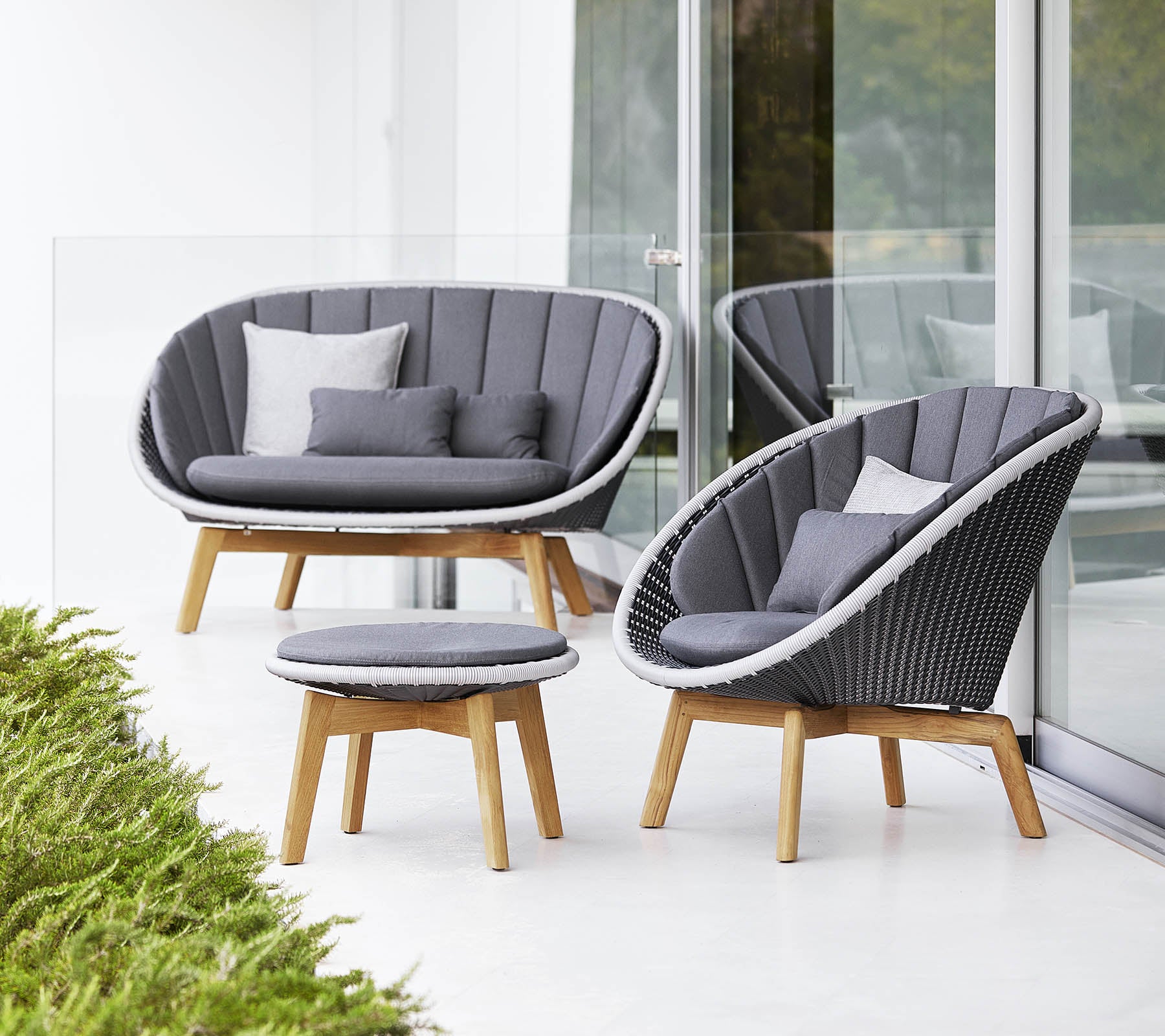 Stylish seating set featuring a curved sofa, chair, and round coffee table, all with a modern design and soft gray cushions.