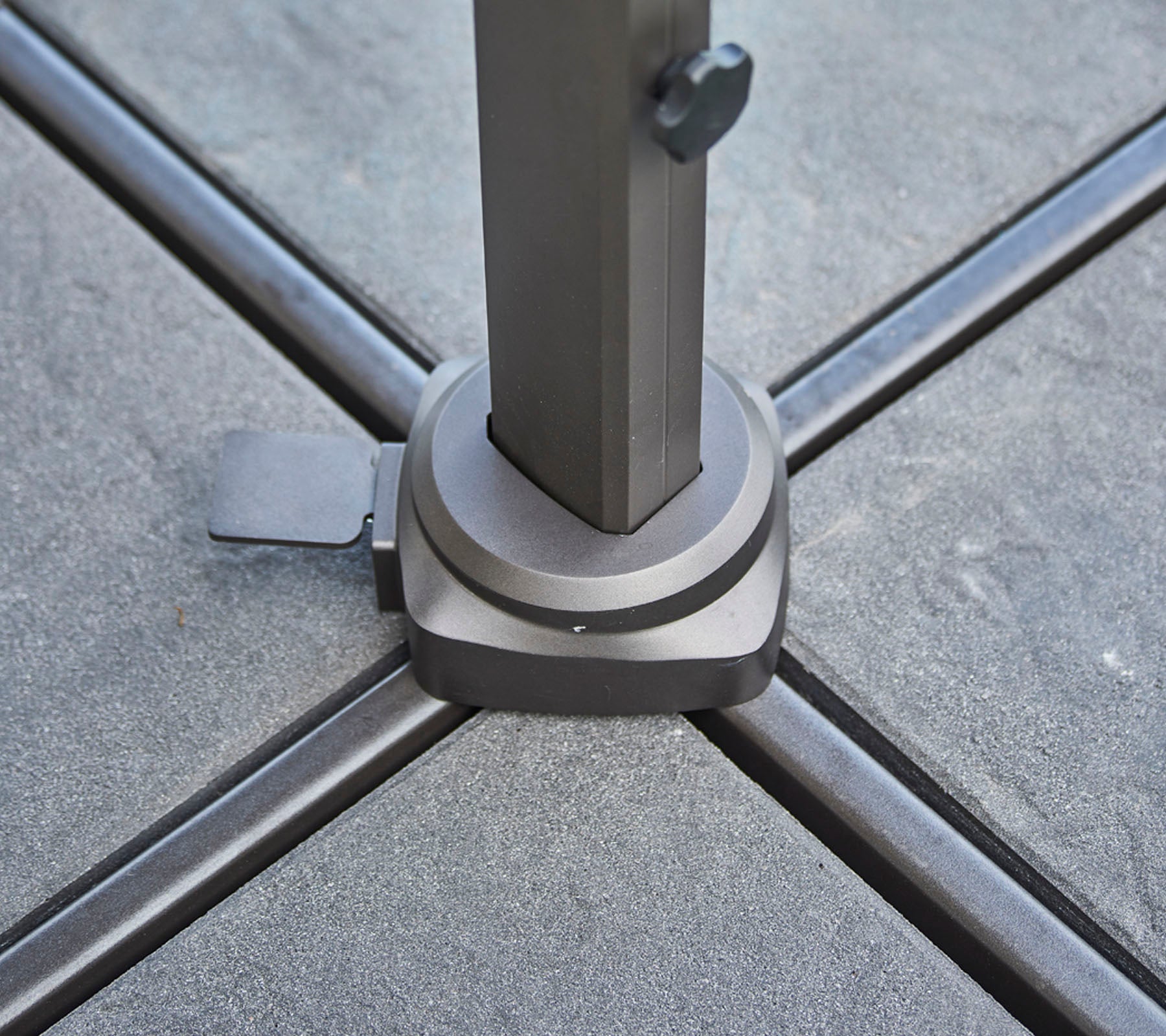 Base of a support pole positioned on a textured surface, featuring a clamp for stability and securing the pole in place.