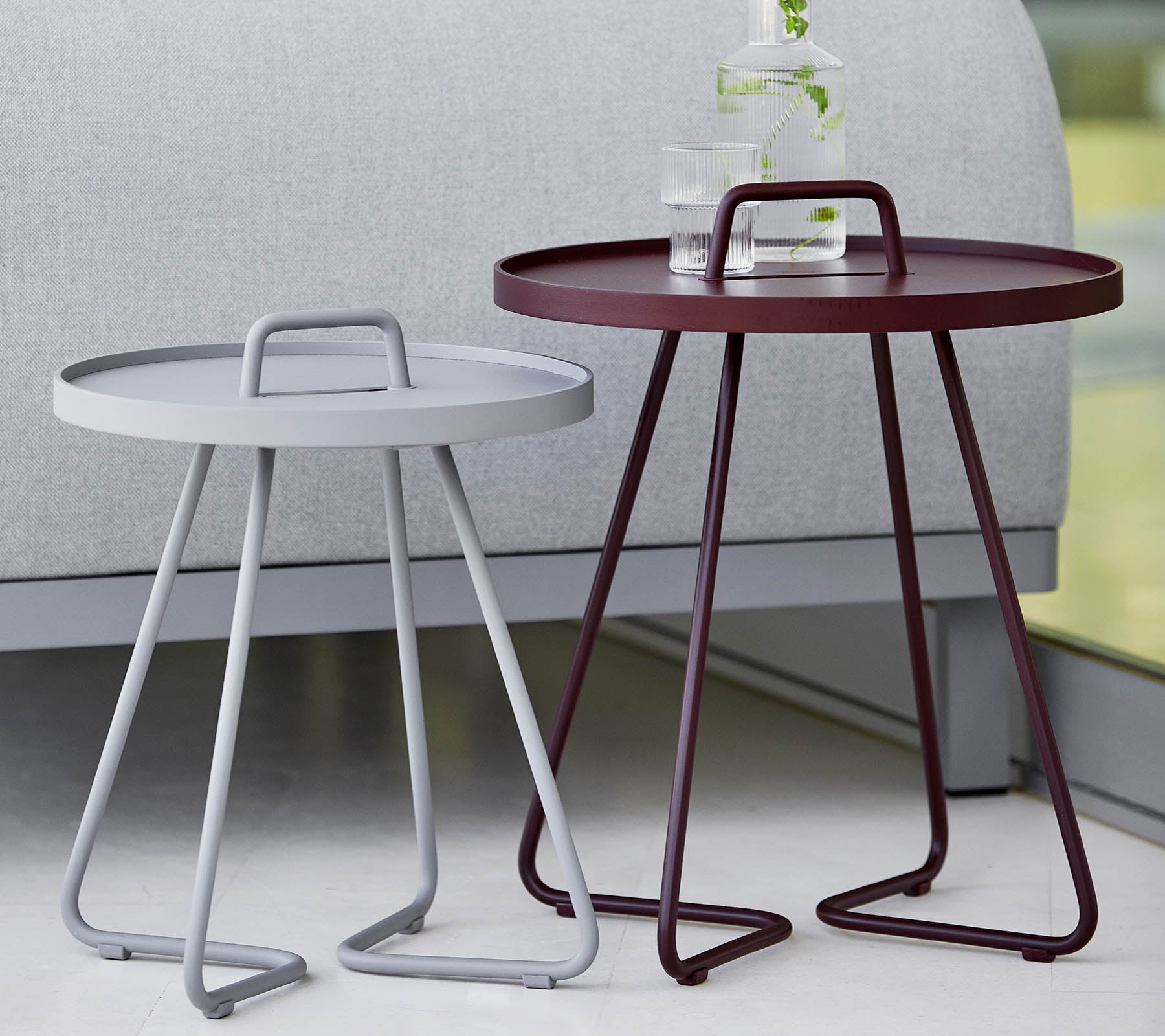 Two modern side tables, one gray and one burgundy, both featuring round trays and stylish tripod legs. Ideal for contemporary decor.