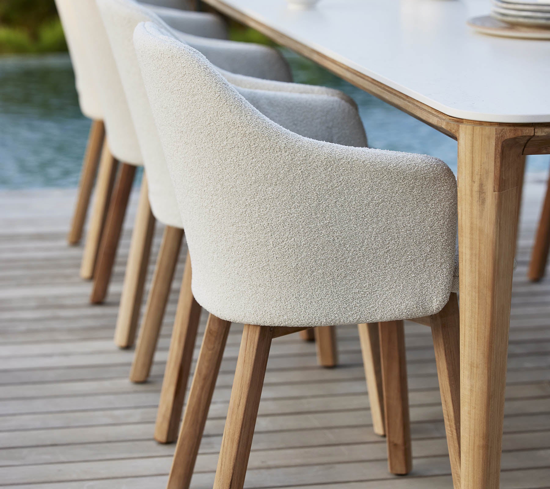 Stylish upholstered chairs with wooden legs lined up next to a table, offering a modern and inviting look for dining or gatherings.