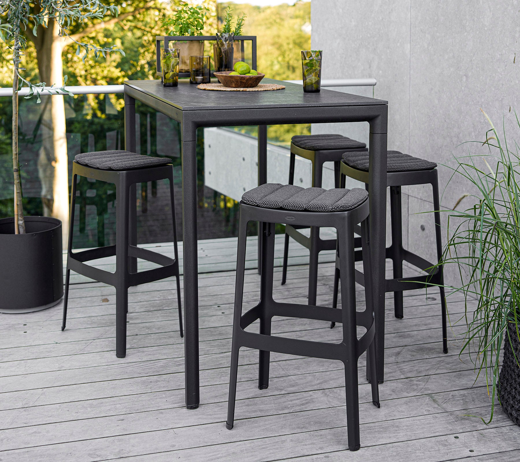 A modern table with four matching stools, featuring a sleek design and a minimalistic aesthetic, set against a natural backdrop.