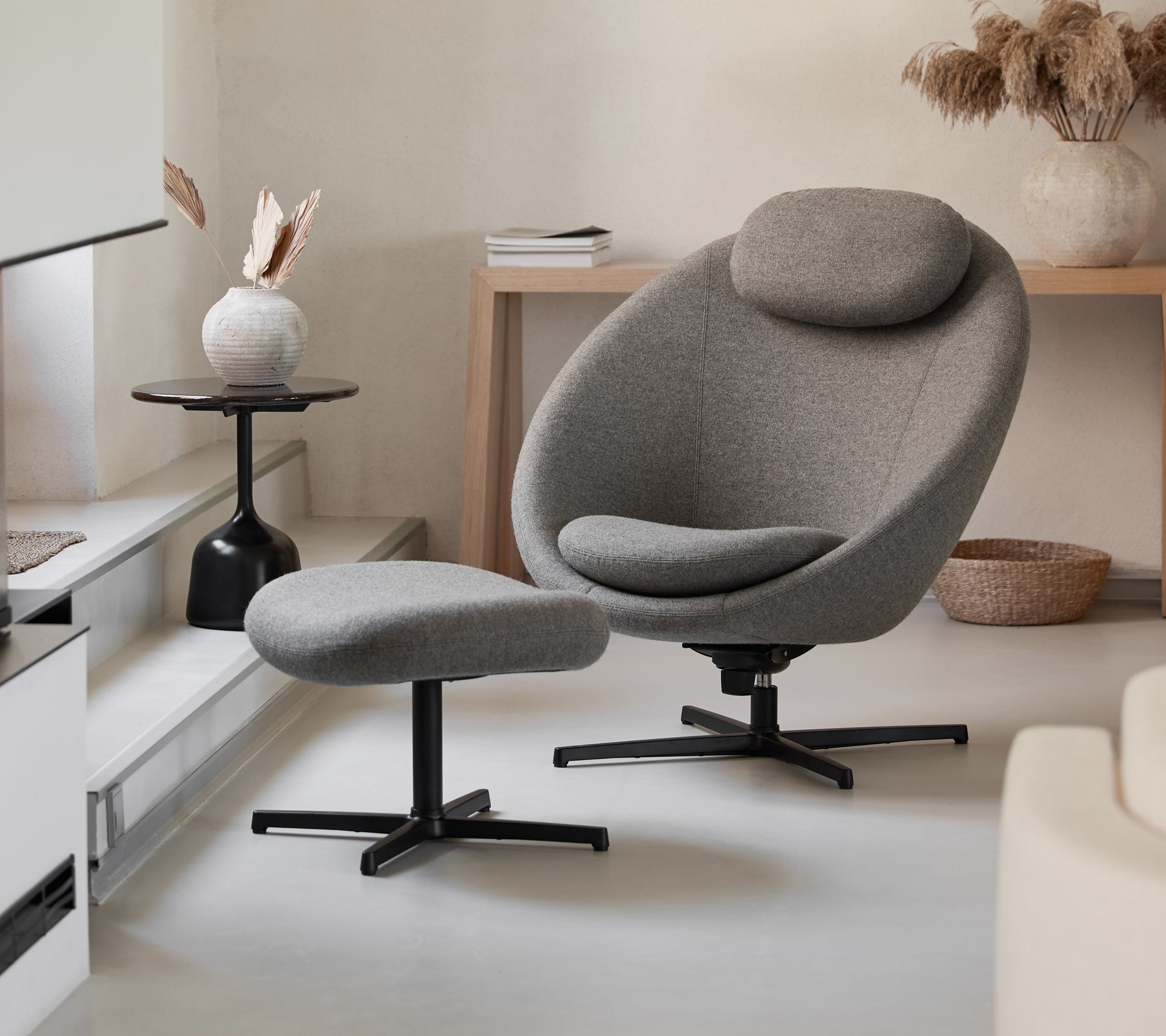 Stylish gray chair with matching ottoman, featuring a sleek design and comfortable curves, complemented by modern decor elements.