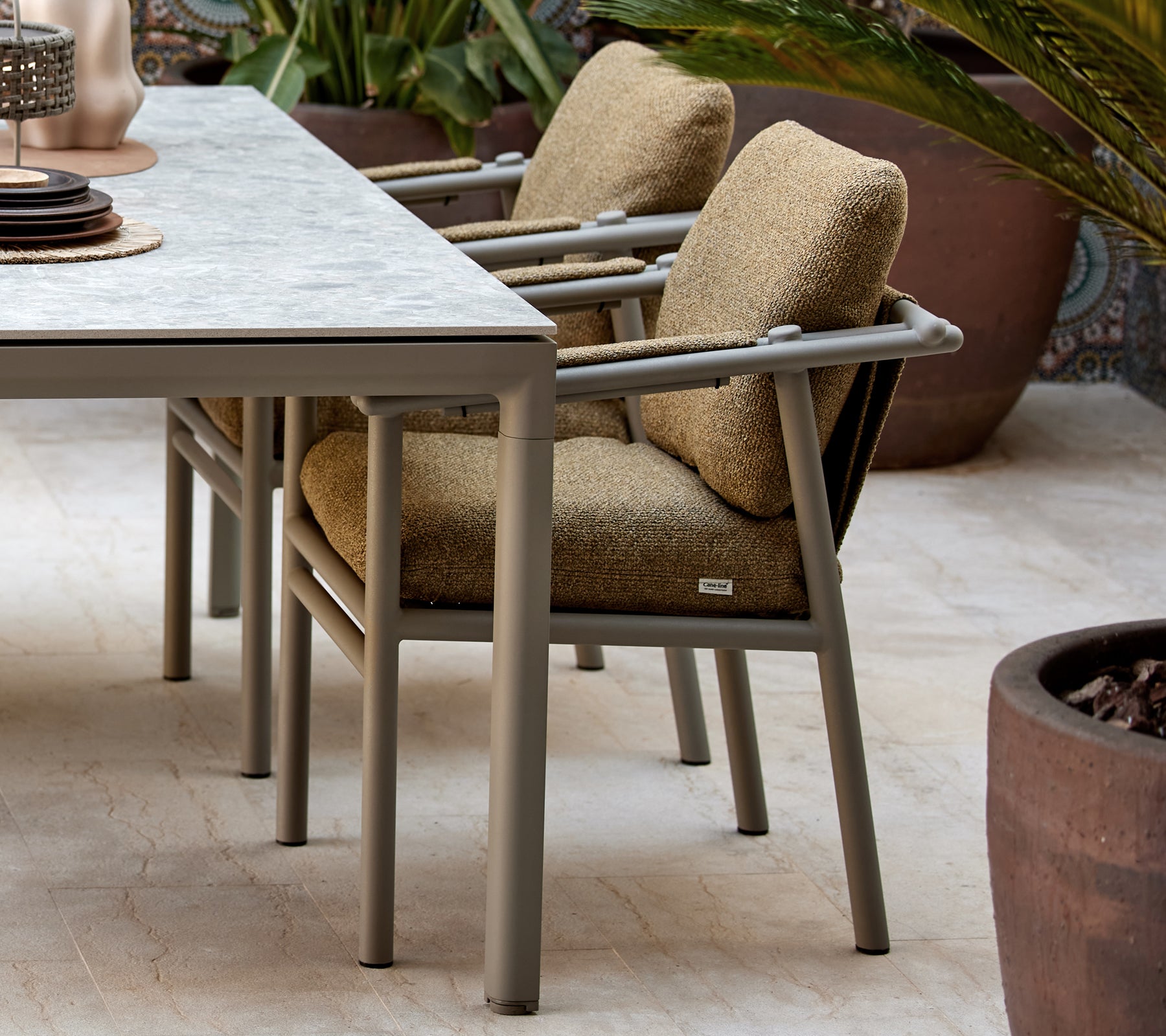 Two dining chairs with soft cushions, featuring a modern design with sturdy sticks, positioned beside a table with decorative items.
